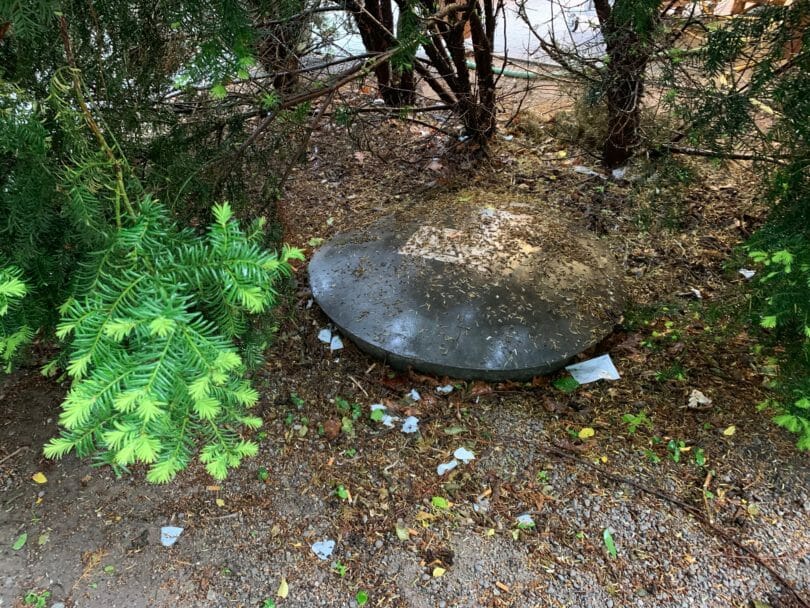 Erdgastank unterirdisch im Garten unter Baum versteckt