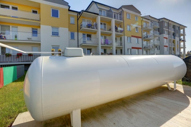 Weißer Flüssiggastank vor Mehrfamilienhaus